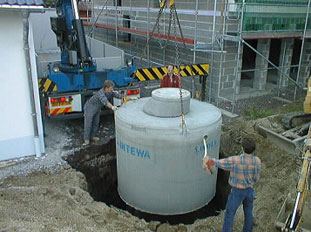 Regenwasserrckhaltung, Betonzisterne Typ FAVORIT-BASIS wird mit einem Autokran in die Baugrube gesetzt